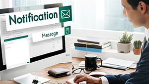 A man in a suit checks his email notifications on a computer